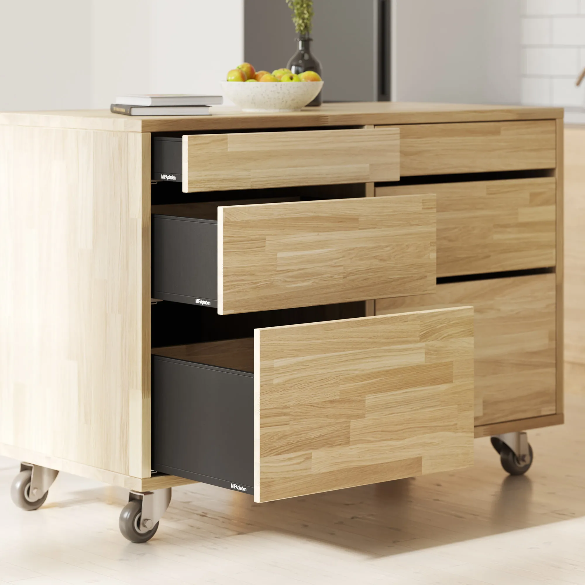 Mobile oak kitchen island on castors with three drawers open at staggered depths, showing solid timber fronts against black carcass interiors.