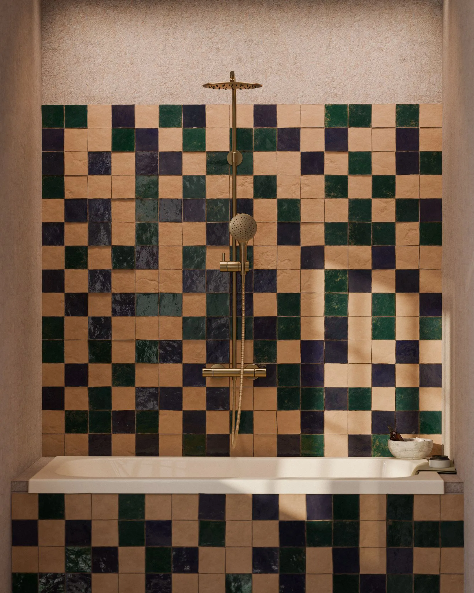 Shower and bath wall in a checkerboard of terracotta, cream, dark green and navy glazed zellige tiles, with a brass rainfall shower column.