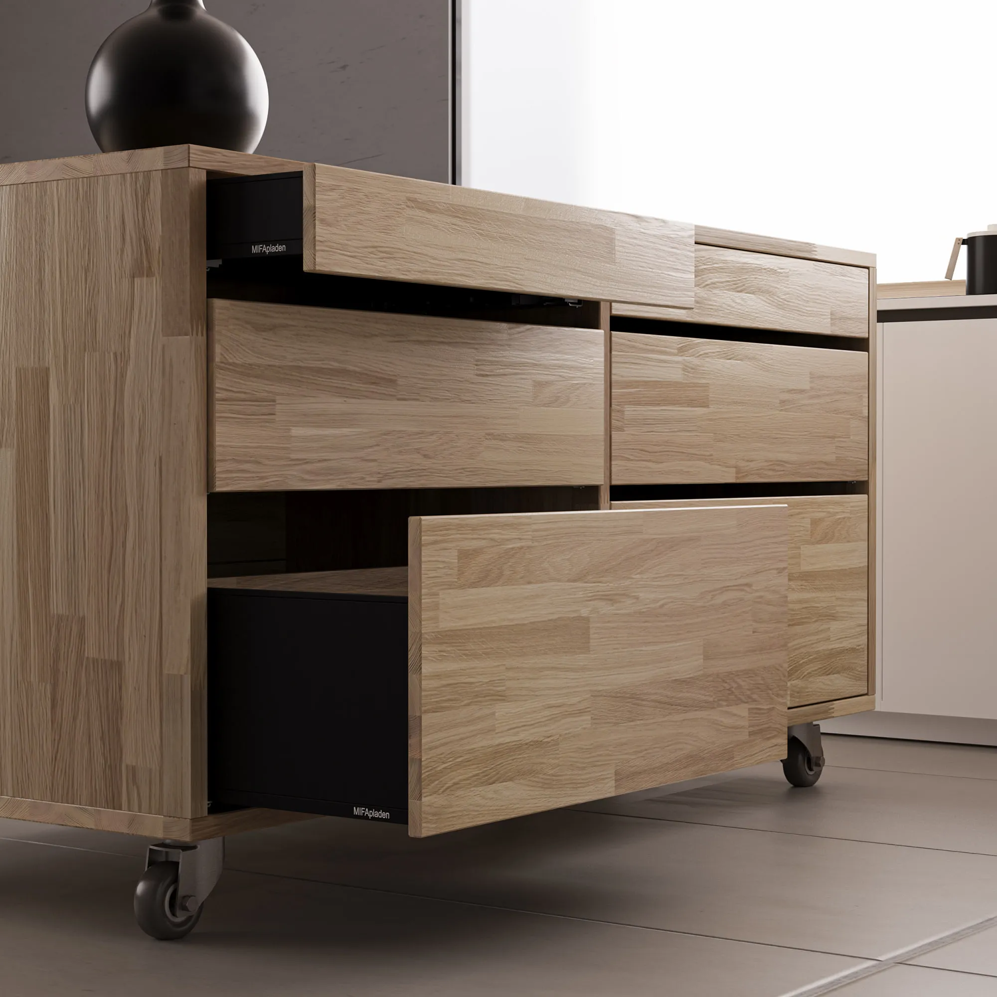 Oak island unit on castors in a darker kitchen, drawers pulled out to show the depth of the black drawer boxes behind solid timber fronts.