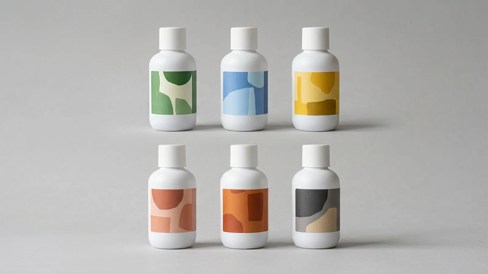 Six identical white bottles in two rows on a pale grey backdrop, each carrying a different coloured abstract label design.